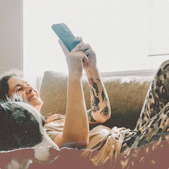A relaxed person wearing leopard-print lounge pants while holding a smartphone