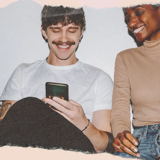 Two smiling people looking at a smartphone together